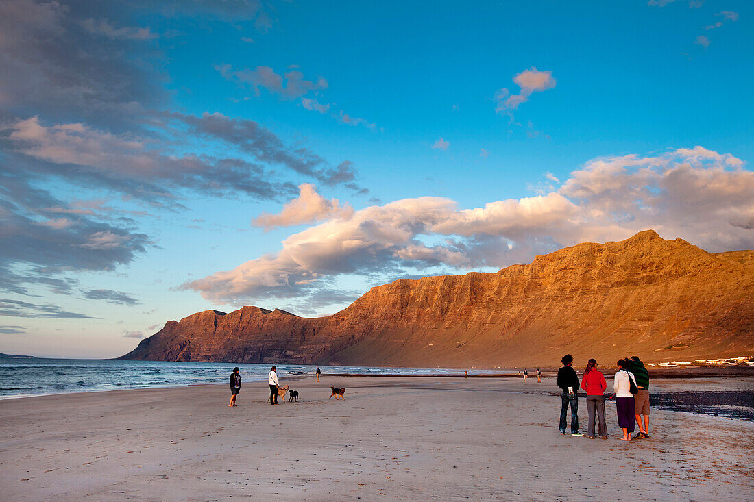 People on the beach in he evening light, Playa de Famara, mountain range Risco de Famara, Lanzarote, Canary Islands, Spain, Europe