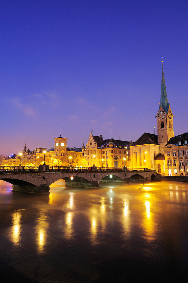 Illuminated buildings and church Frauenmuenster with river Limmat in foreground, Zurich, Switzerland