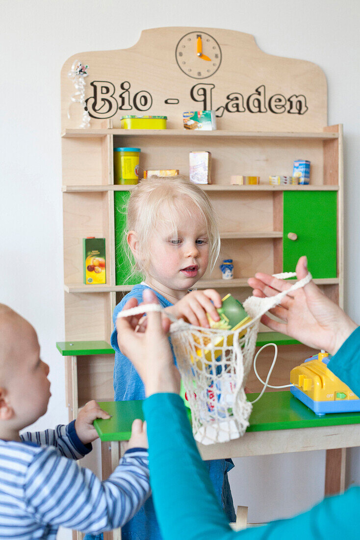 Kleiner Junge und kleines Mädchen spielen miteinander, Bio-Laden, Kaufmannsladen, Spielzeug, Junge 9 Monate alt, Mädchen 2 Jahre alt, MR, Bad Oeynhausen, Nordrhein-Westfalen, Deutschland