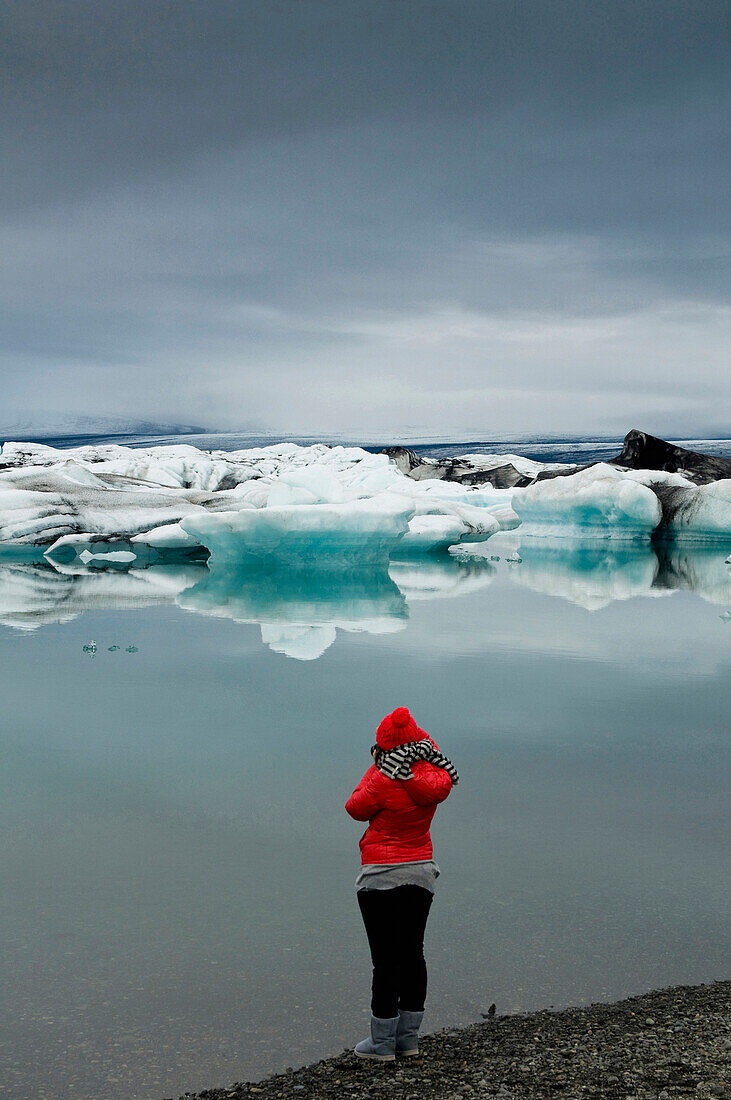 Person standing on the edge of the glecial lagoon, Jokulsarlon, Iceland, Scandinavia, Europe
