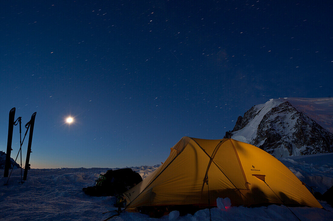 Moon and starry sky over tent at dawn, view towards Mont Blanc du Tacul, Chamonix, Mont-Blanc, France
