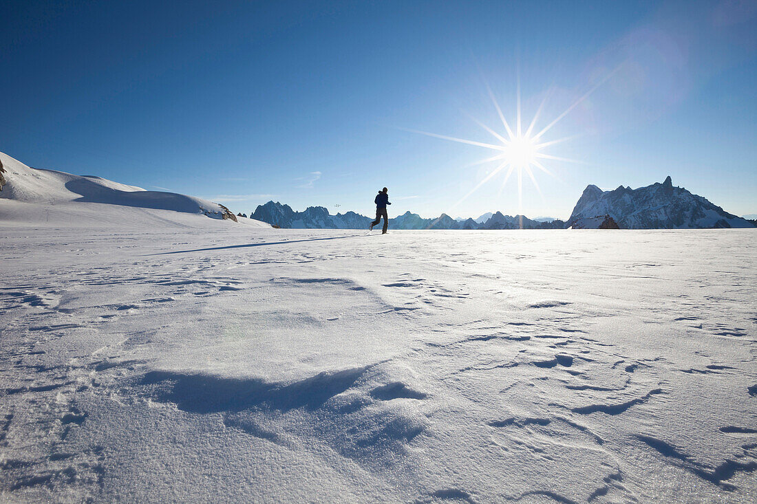 Mann läuft bei Sonnenaufgang über Gletscher, Blick zu Les Grandes Jorasses und Dent du Geant, Chamonix Mont Blanc, Frankreich, Europa