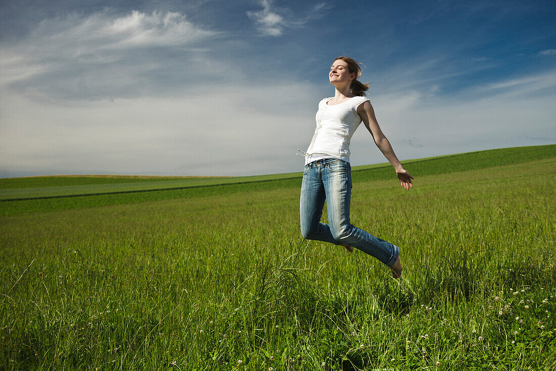 Girl jumping barefoot in a meadow, Upper Bavaria, Germany