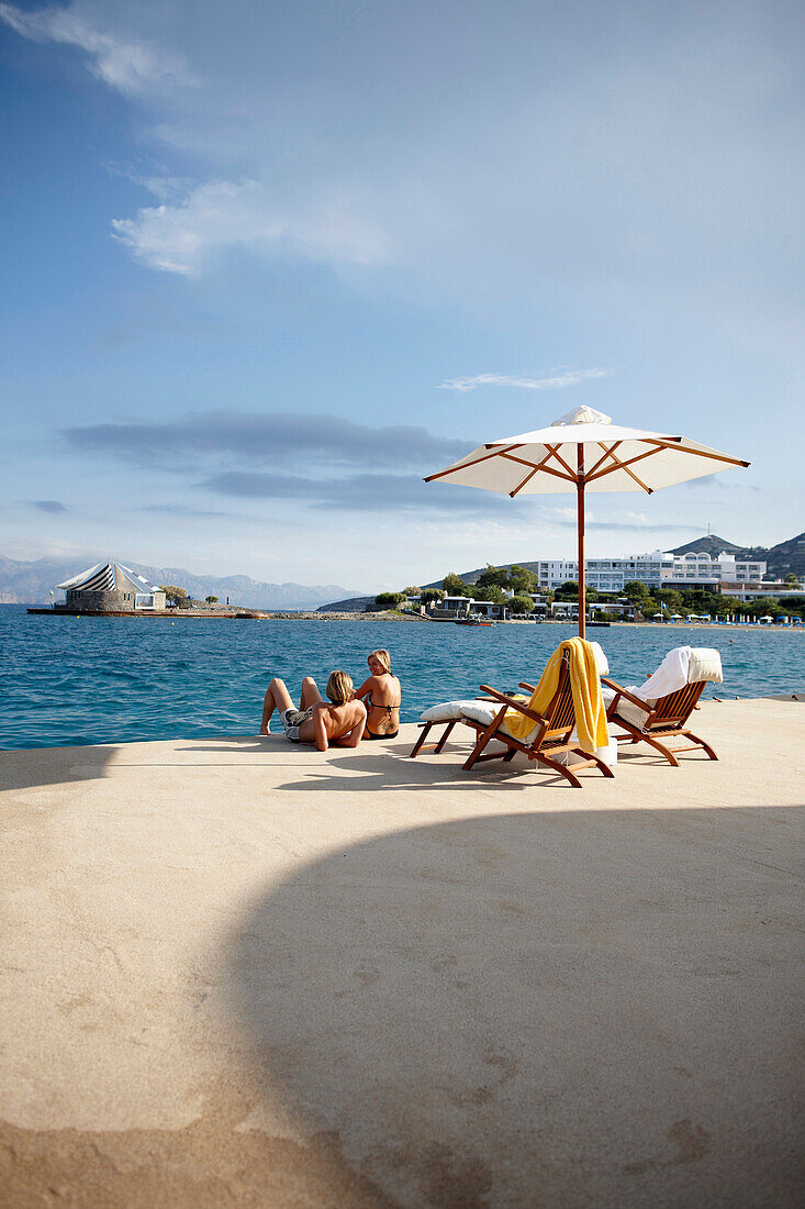 Couple sunbathing on the terrace of the Yachting Club,  Beach Resort, Elounda, Crete, Greece