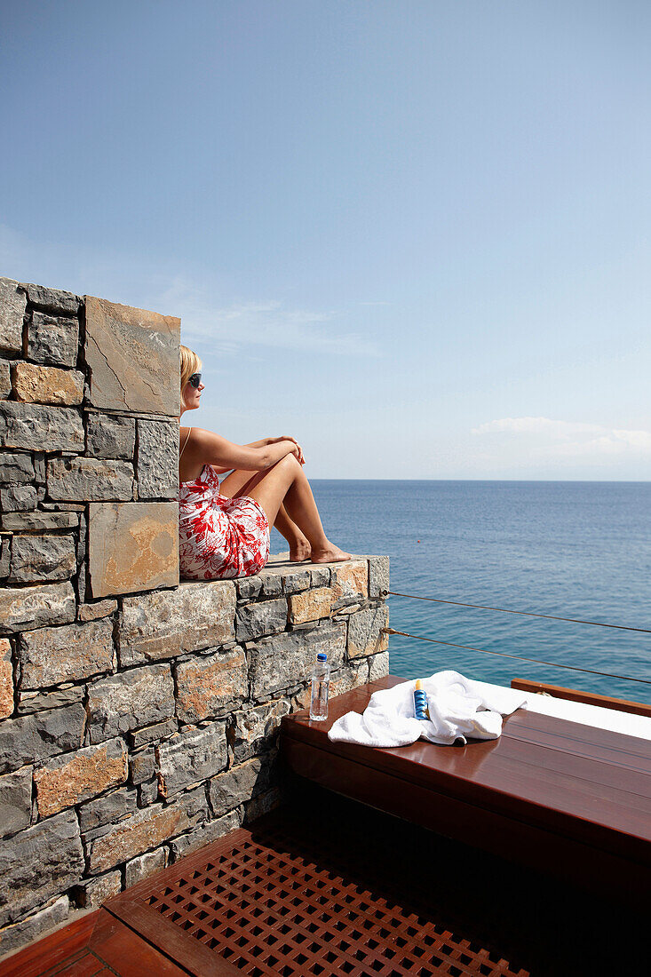 Frau auf Steinstufen sitzend, Blick aufs Meer, Elounda Beach Resort, Elounda, Kreta, Griechenland