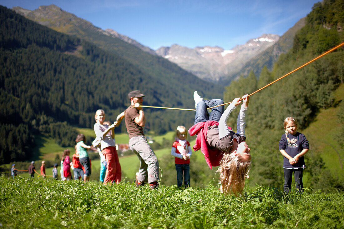 Girl making her way hand over hand along a rope, Gossensass, Brenner, South Tyrol, Trentino-Alto Adige/Suedtirol, Italy