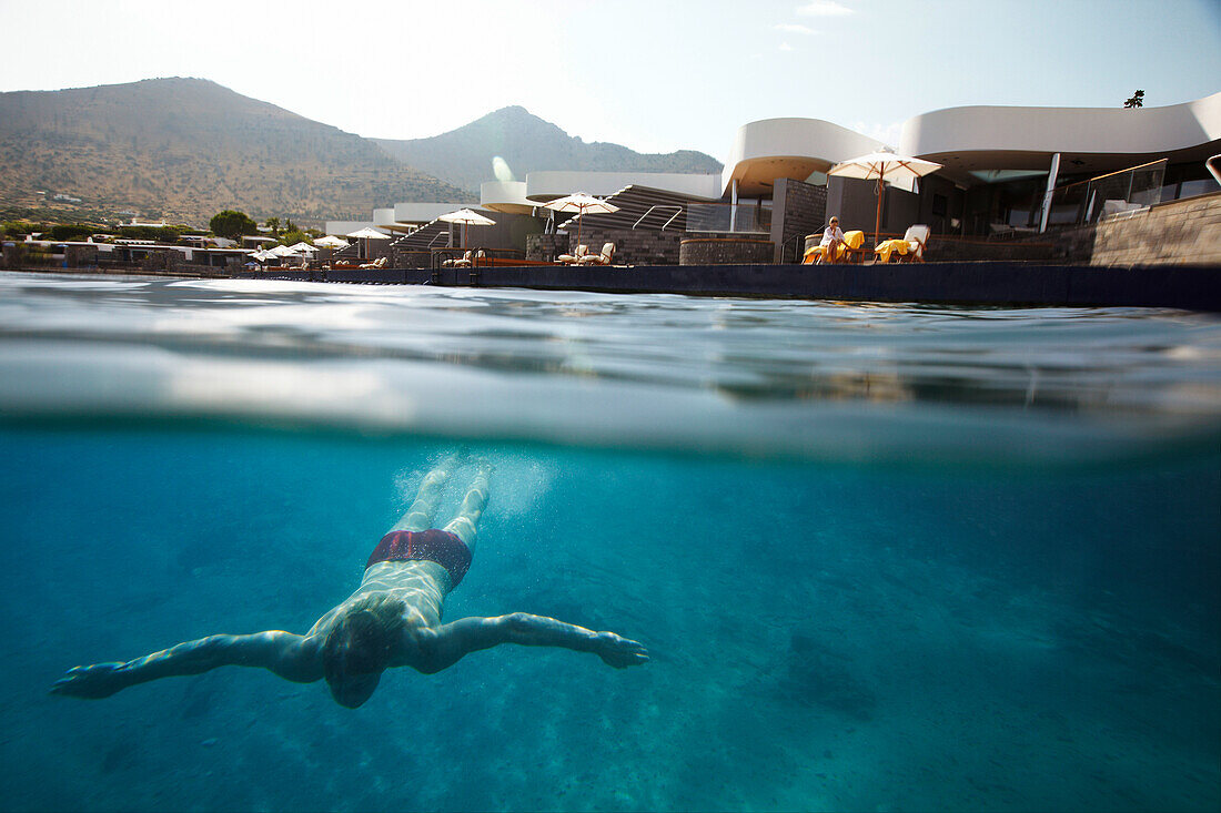 Diver underwater in front of Yachting Club, Elounda, Crete, Greece