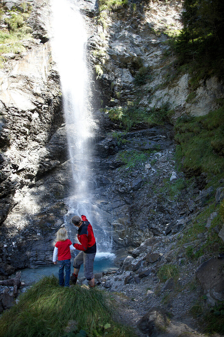 Girl and mountain guide in front of a waterfall, Gossensass, Brenner, South Tyrol, Trentino-Alto Adige/Suedtirol, Italy