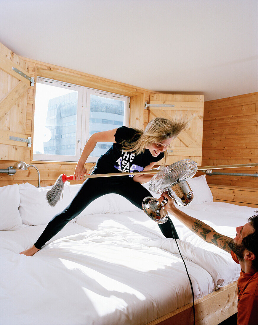 Woman playing air guitar with a mop brush on a bed sleeping eight people, Hotelroom, Zeeburg, Amsterdam, Netherlands