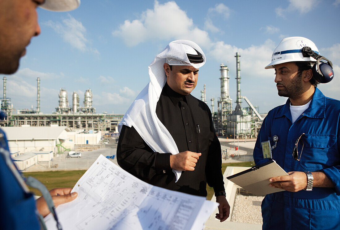 Men having a meeting, refinery in background, Ras Laffan Industrial City, Qatar