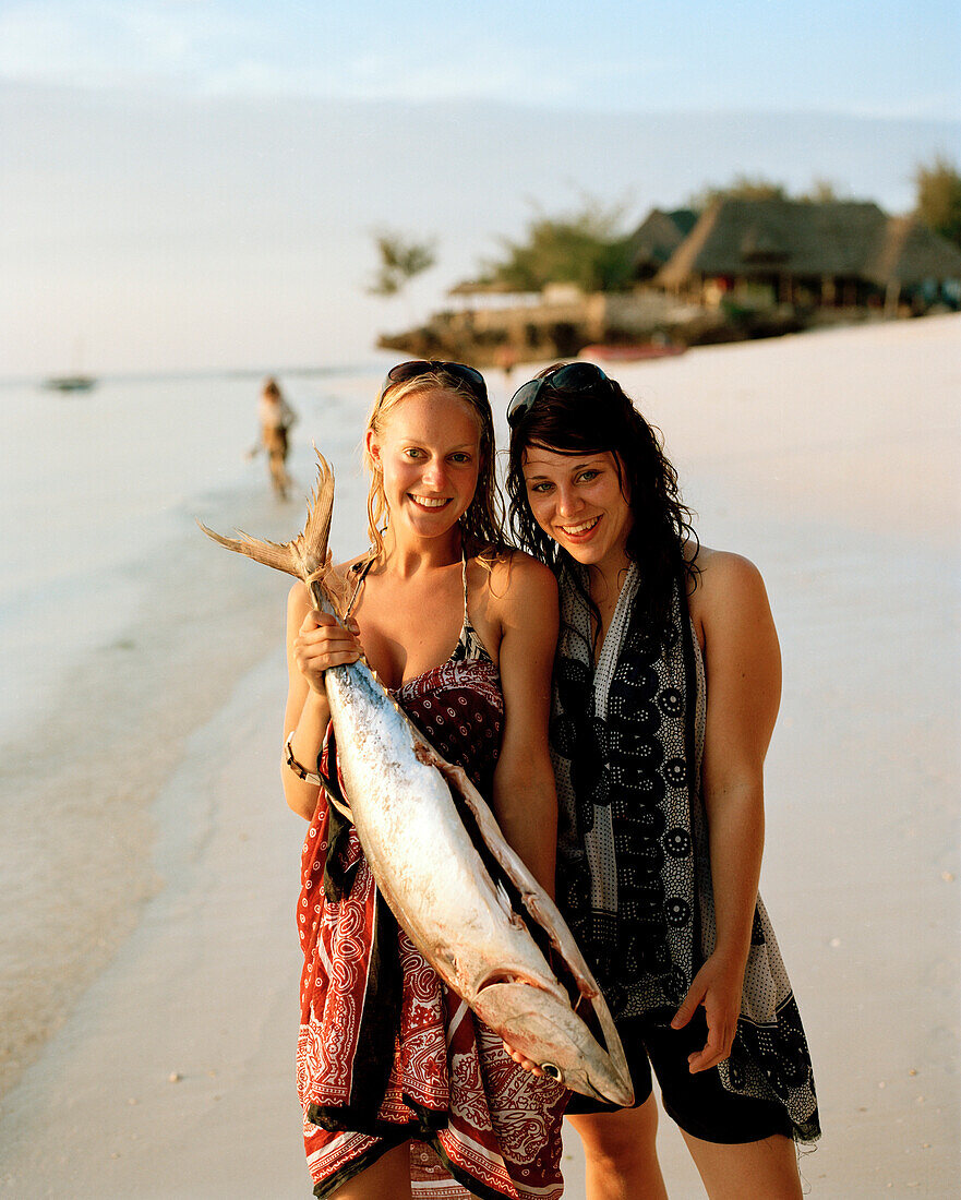 Touristinnen mit vom Fischer gekauften Yellowtail Tuna, Thunfisch, für Geburtstagsfeier, Nungwi, Sansibar, Tansania, Ostafrika