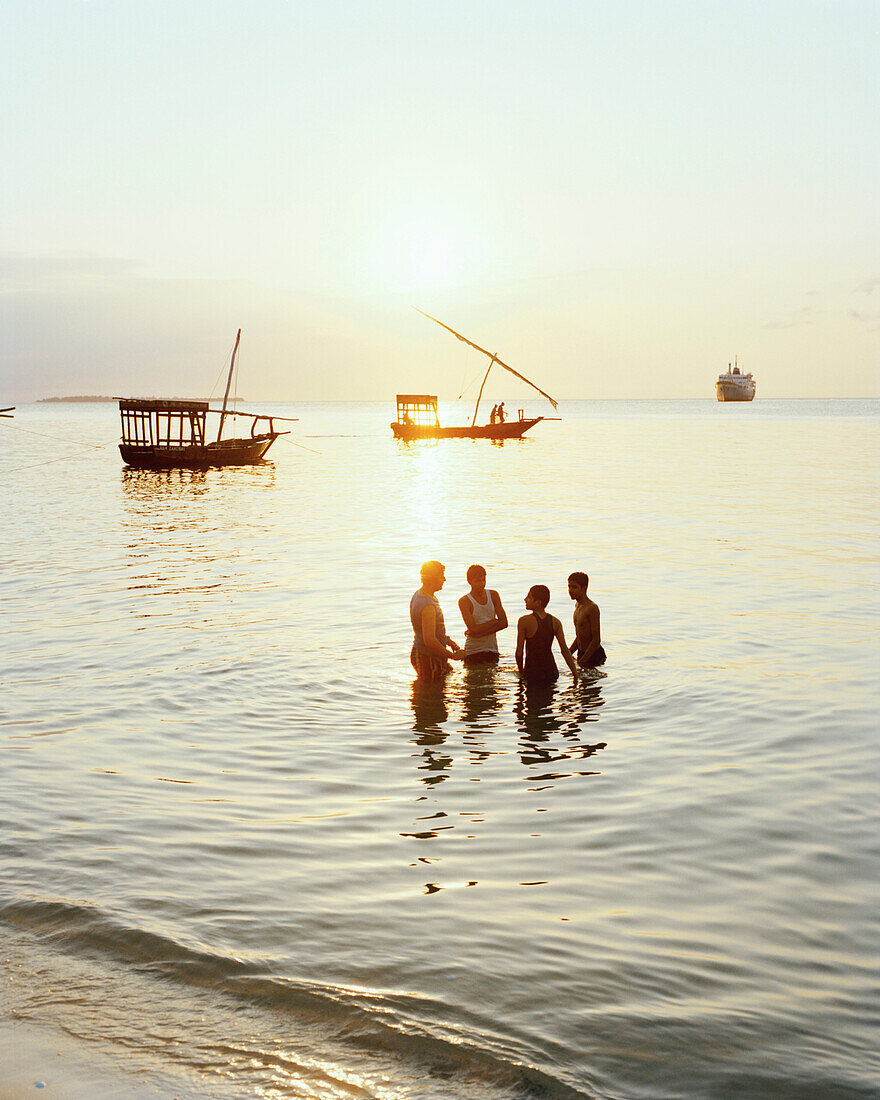 Jungen baden abends an Forodhani Strand, Frachtschiff, Dhows an Westspitze der Stone Town, Sansibar, Tansania, Ostafrika