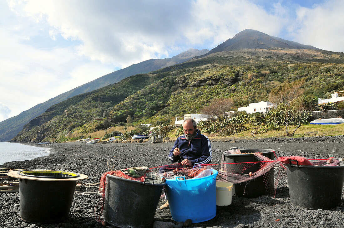 Fischer entwirrt sein Netz, am Strand auf der Insel Stromboli, Insel Stromboli, Liparische Inseln, Sizilien, Italien