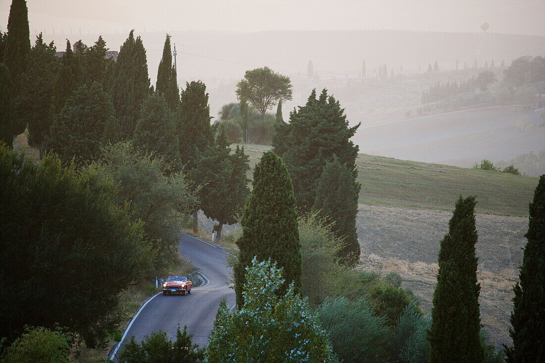 Oldtimer auf einer Landstrasse bei Montalcino in der Abenddämmerung, Toskana, Italien, Europa