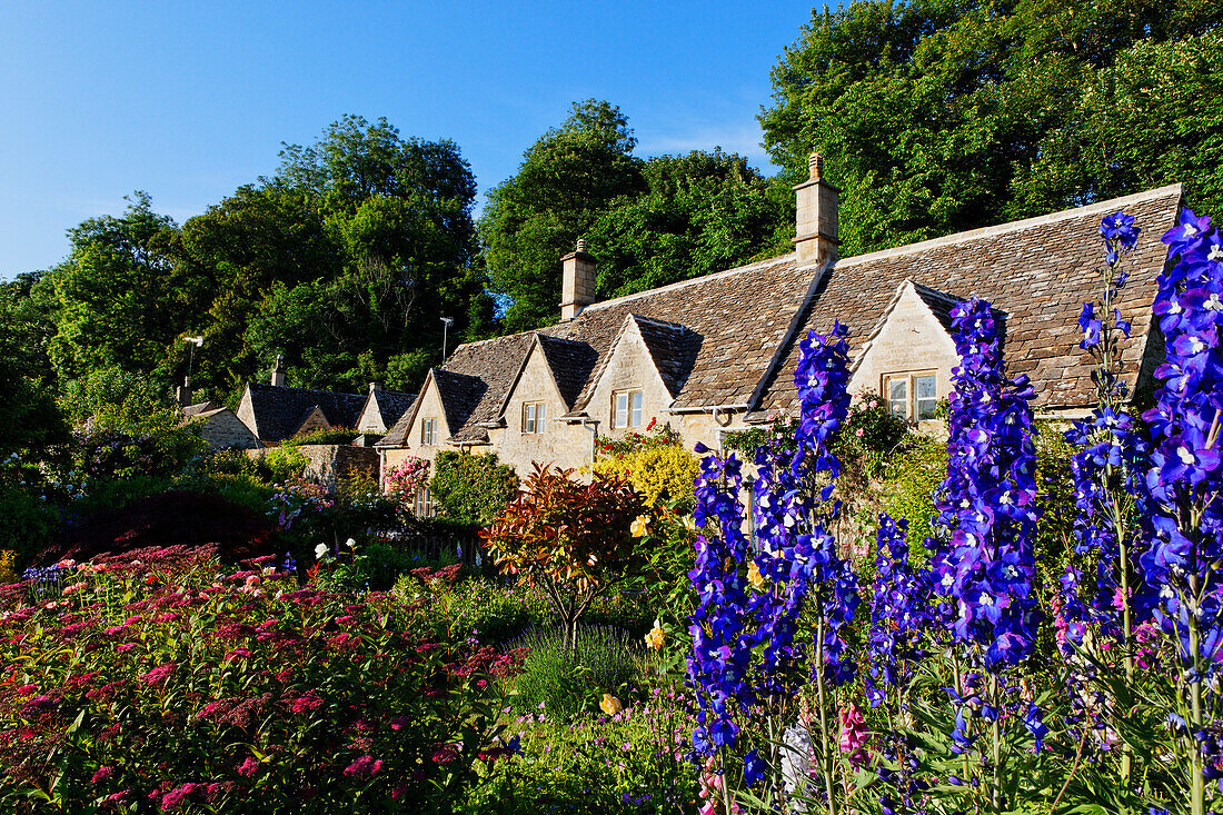 Häuser und Blumen im Sonnenlicht, Bibury, Gloucestershire, Cotswolds, England, Großbritannien, Europa