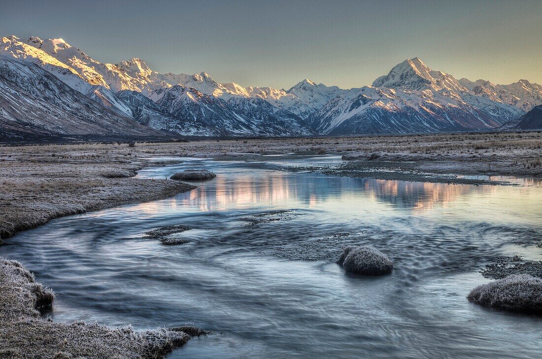 Dawn lights up eastern faces of Aoraki/ mt Cook from frosted grass Tasman River flats, Aoraki / Mt cook National Park, New Zealand