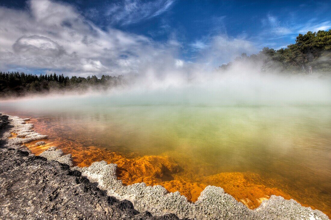 Champagne pool, burst of sunshine lights up foreshore during day of blowing mist and heavy rain, Wai-o-Tapu thermal region, Rotorua