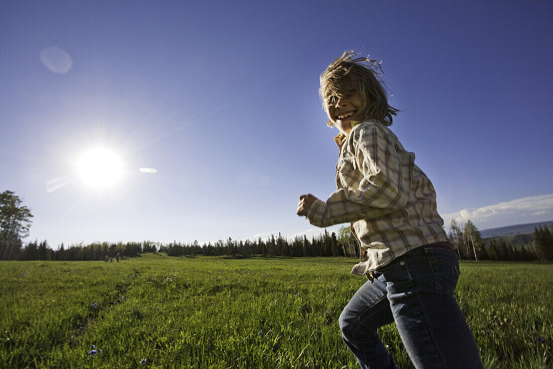Smiling Young Girl Running in Grass Field, Oak Creek, Colorado, USA