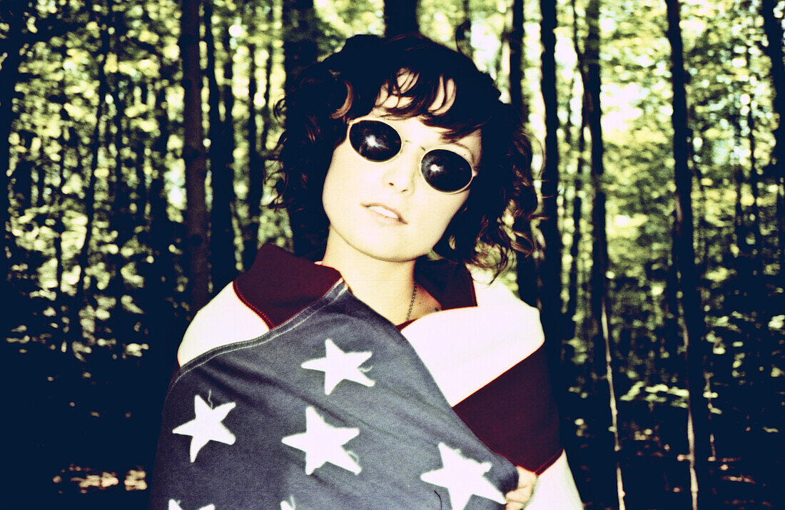 Junge Frau mit Sonnenbrille und in die amerikanische Flagge gehüllt