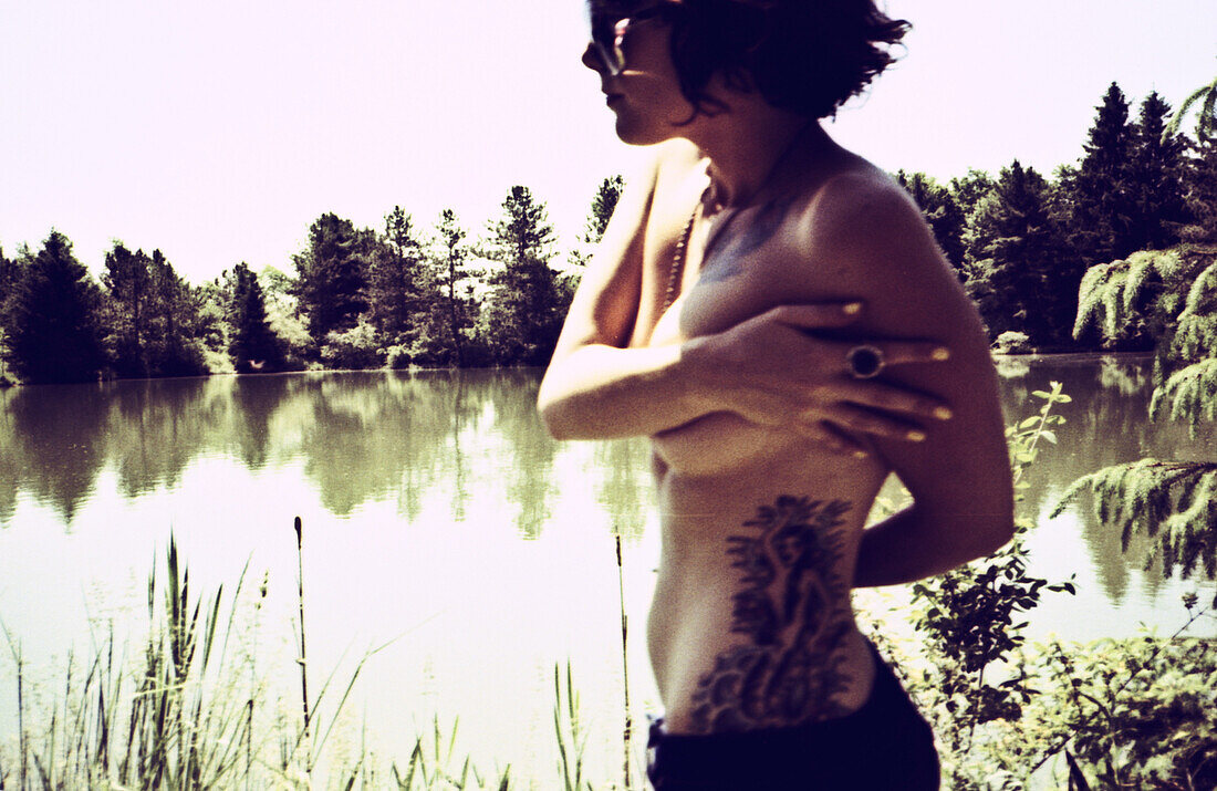 Topless Young Woman With Tattoos Standing by Lake