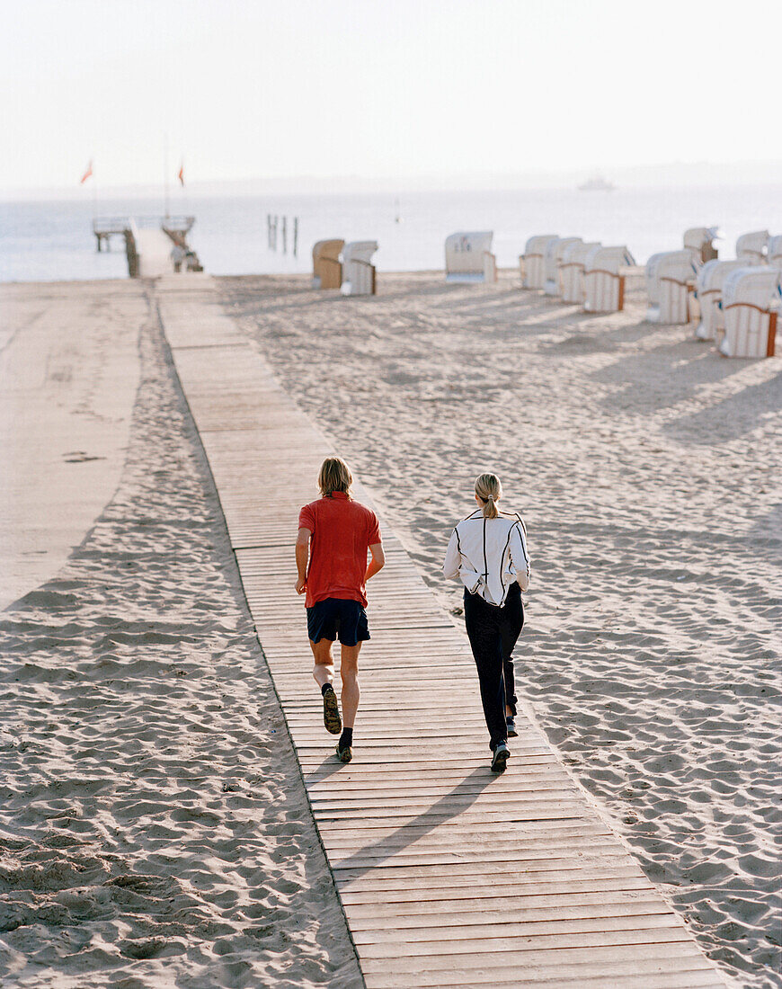 Paar joggt am Ostseestrand, Arosa Spa Resort Travemünde, Travemünde, Lübeck, Schleswig-Holstein, Deutschland