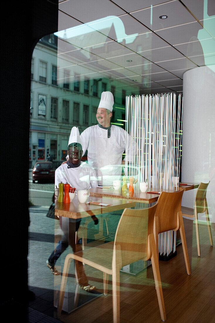 Cooks in the restaurant and reflection in the front window of Hotel BLOOM, Brussels, Belgium