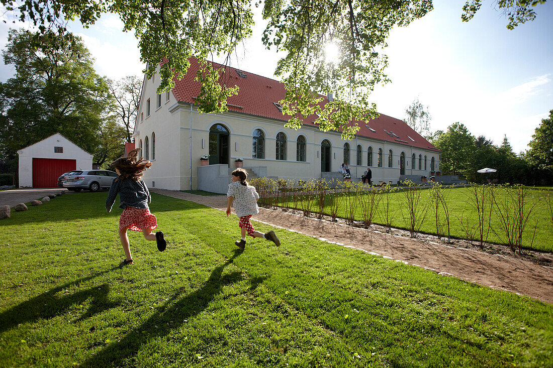 Children running over a meadow near a hotel, Fincken, Mecklenburg-Western Pomerania, Germany