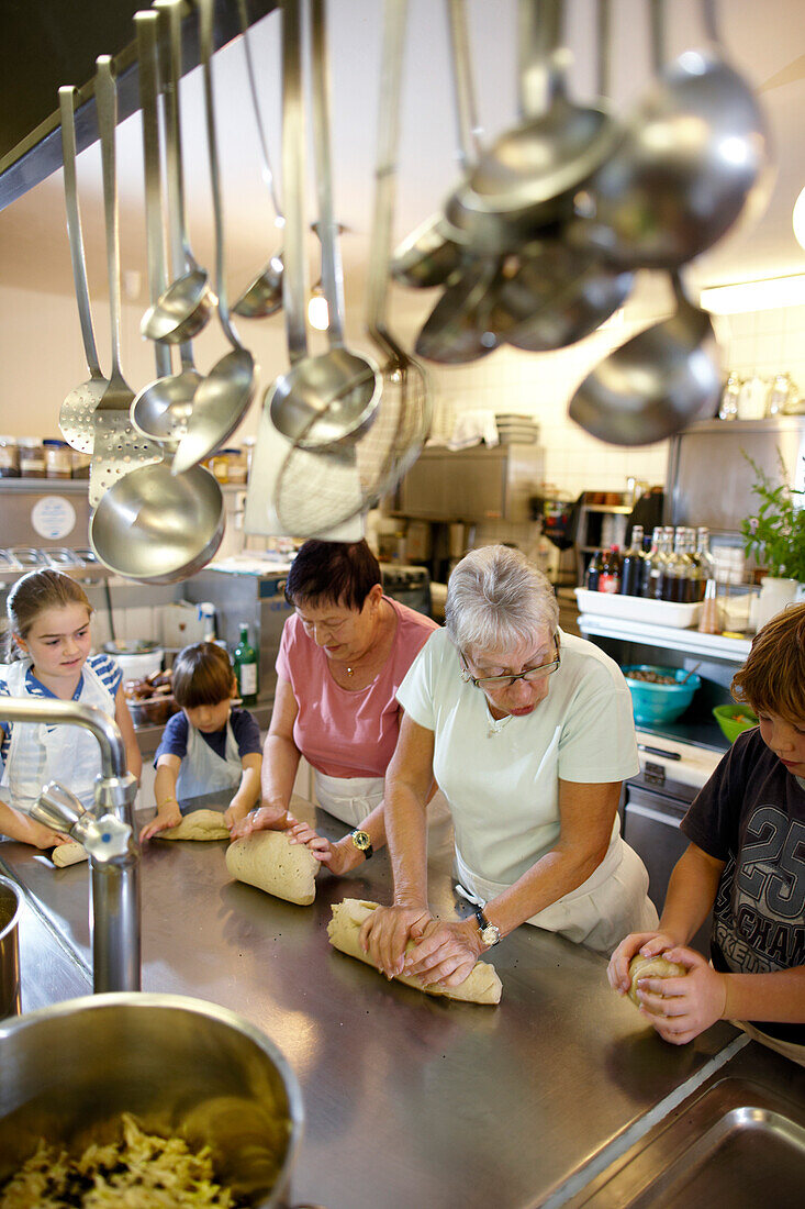 Women and children baking in a hotel kitchen, Am Hochpillberg, Schwaz, Tyrol, Austria