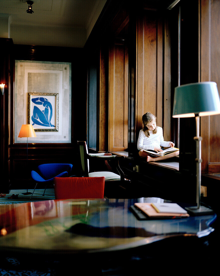 Mädchen sitzt auf einer Fensterbank und liest, Directors Room 207, Hotel New York, Kop van Zuid, Rotterdam, Niederlande