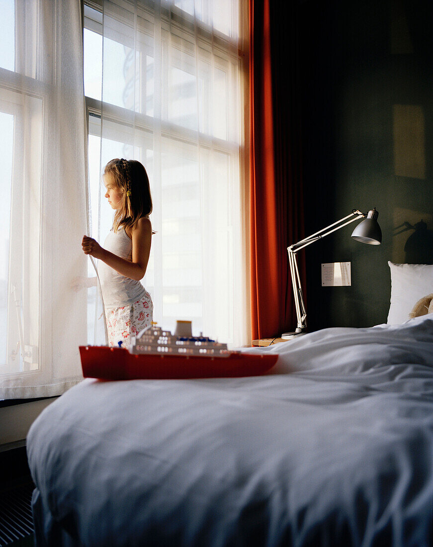 Girl looking out of a hotel window, Rotterdam, Netherlands