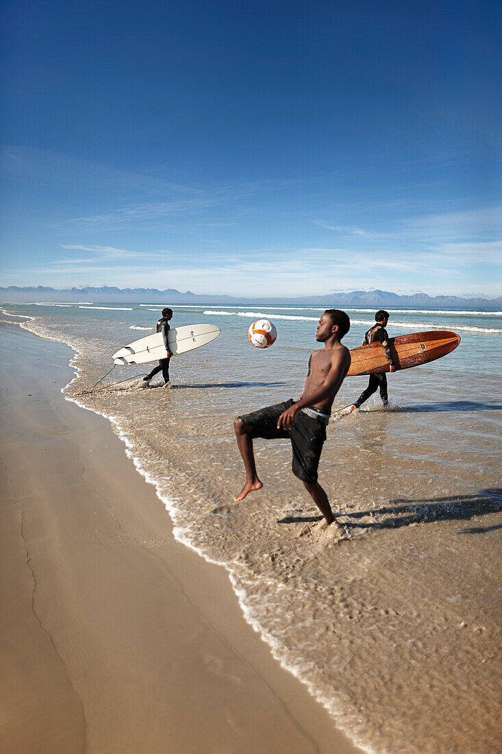 Surfer playing football on the beach, Muizenberg, Peninsula, Cape Town, South Africa, Africa