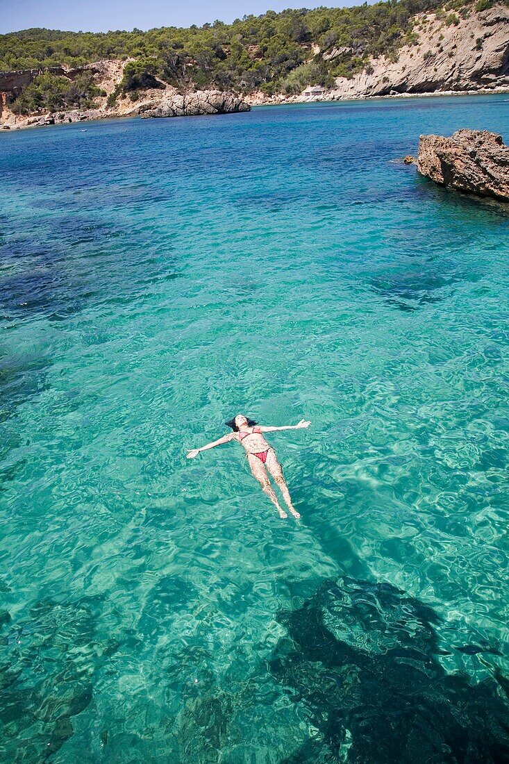 Woman floating in water at a beach in Portinatx, Ibiza, Balearic Islands, Spain