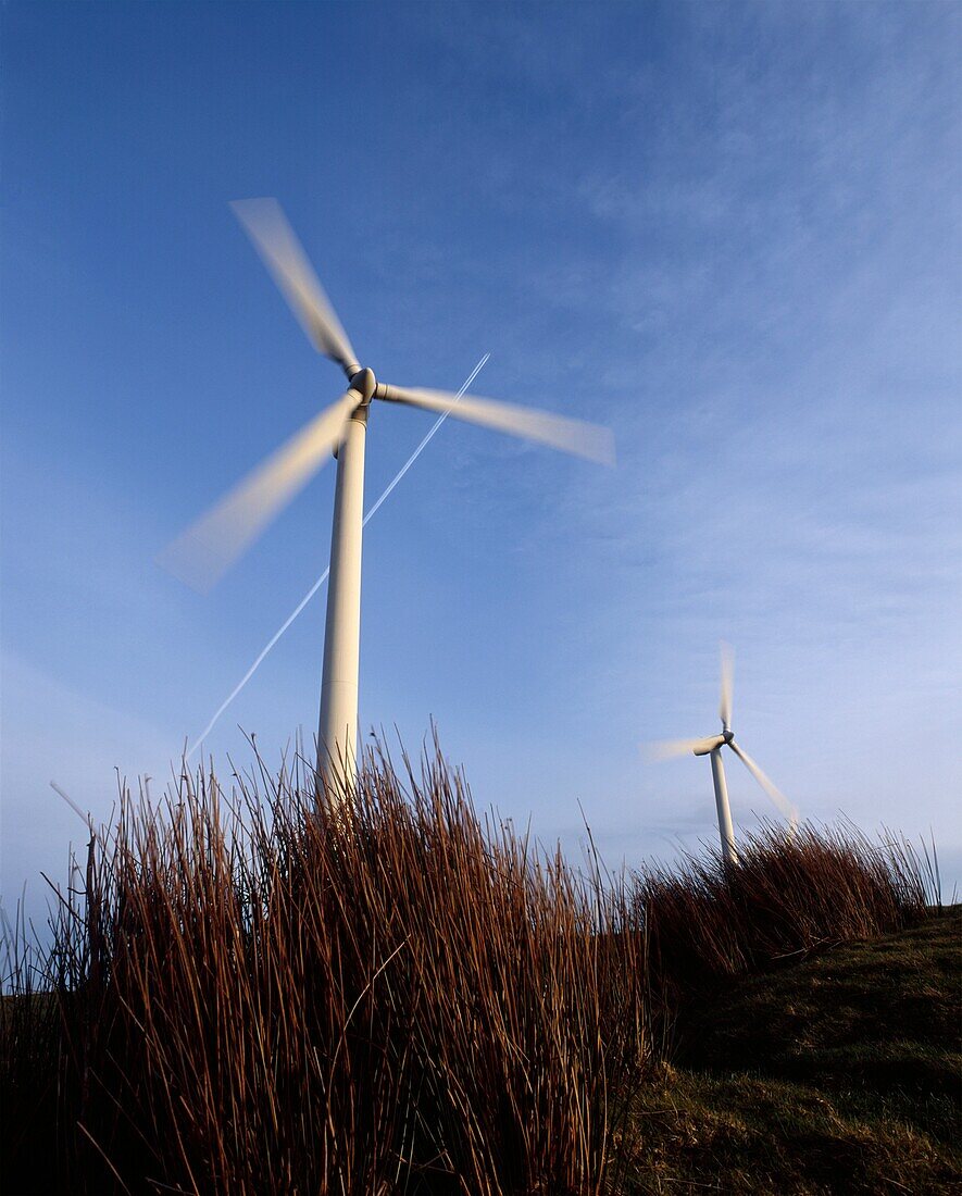 An airliner flies over two wind turbines at the Gilfach Goch Wind Farm near Bridgend and Pontypridd, Mid Glamorgan, Wales, United Kingdom