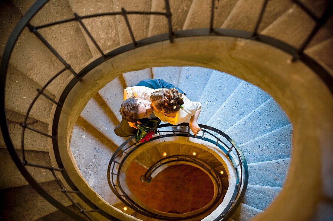 Bride and groom kissing on spiral stairs