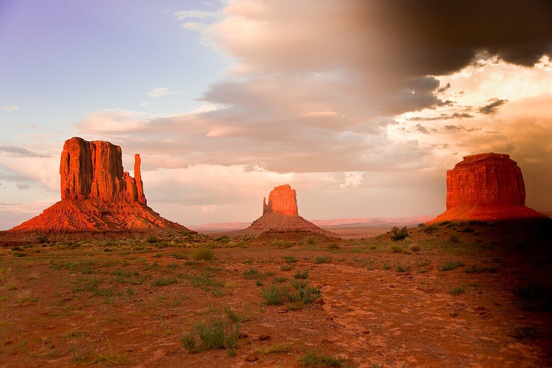Massive sandstone pillars soar above iconic Monument Valley at sunset at sunset