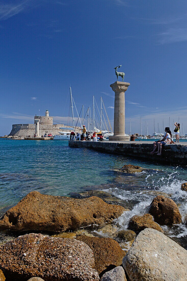Columns at the entrance of Mandraki harbour and the Agios Nikolaos Fortress in the sunlight, Rhodes town, Rhodes, Dodecanese Islands, Greece, Europe