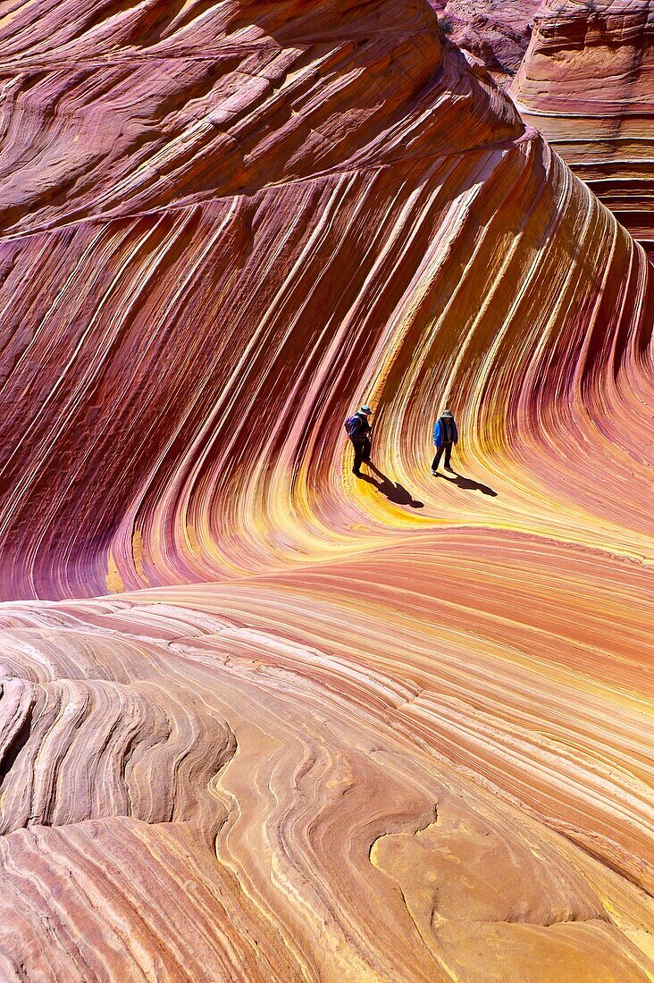 Hikers exploring ´The Wave´, a 190 million year old Jurassic-age Navajo sandstone rock formation, Coyote Buttes, Paria Canyon-Vermillion Cliffs Wilderness Area, Utah-Arizona border, USA