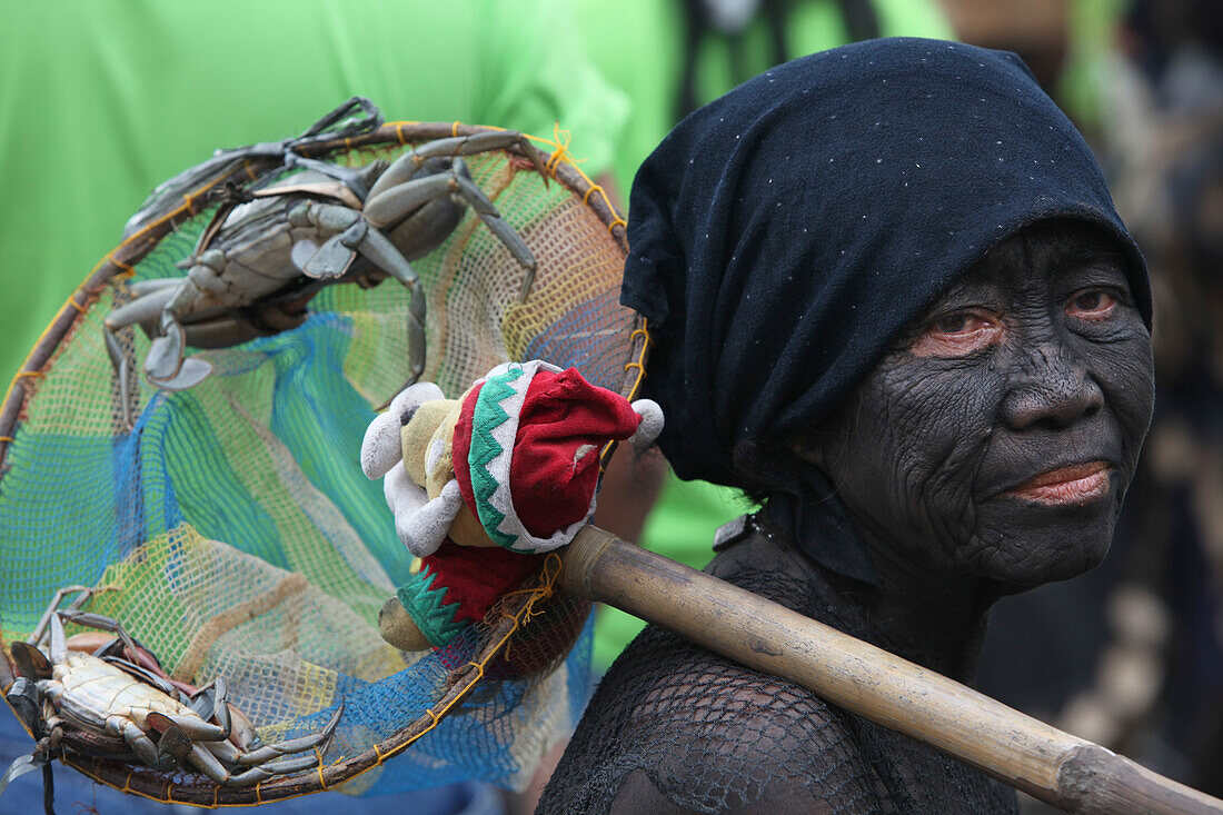 Woman with facial painting holding offerings at Ati Atihan festival, Ibajay, Aklan, Panay Island, Visayas, Philippines
