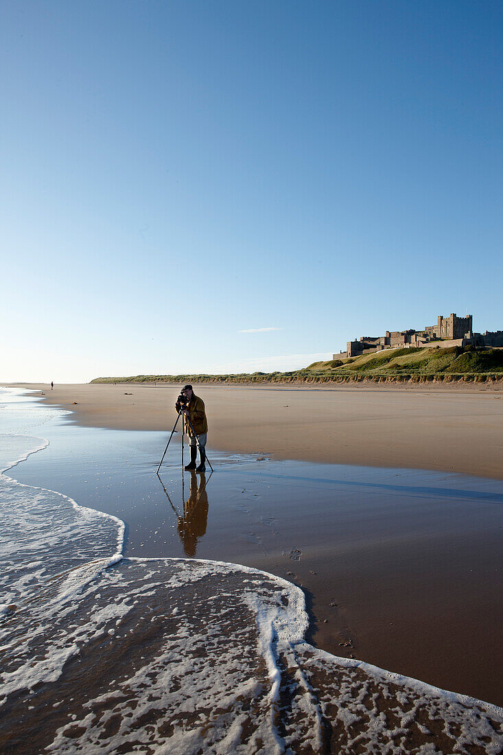 Fotograf am Strand unterhalb Bamburgh Castle, Bamburgh, Northumberland, England, Grossbritannien, Europa