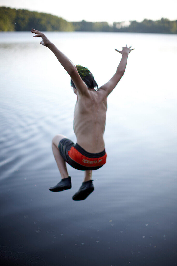 Boy juming into lake Goldensee, Klein Thurow, Roggendorf, Mecklenburg-Western Pomerania, Germany