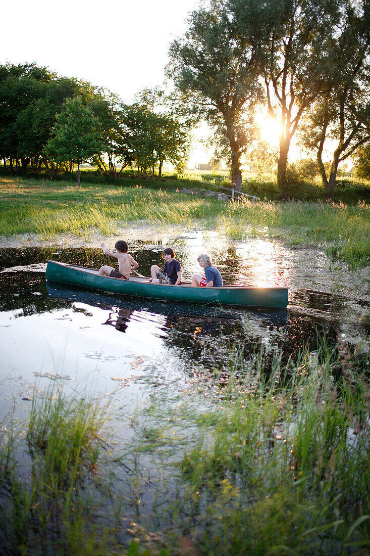 Drei Jungen in einem Kanu auf einem Teich, Haus Strauss, Bauernkate in Klein Thurow, Roggendorf, Mecklenburg-Vorpommern, Deutschland