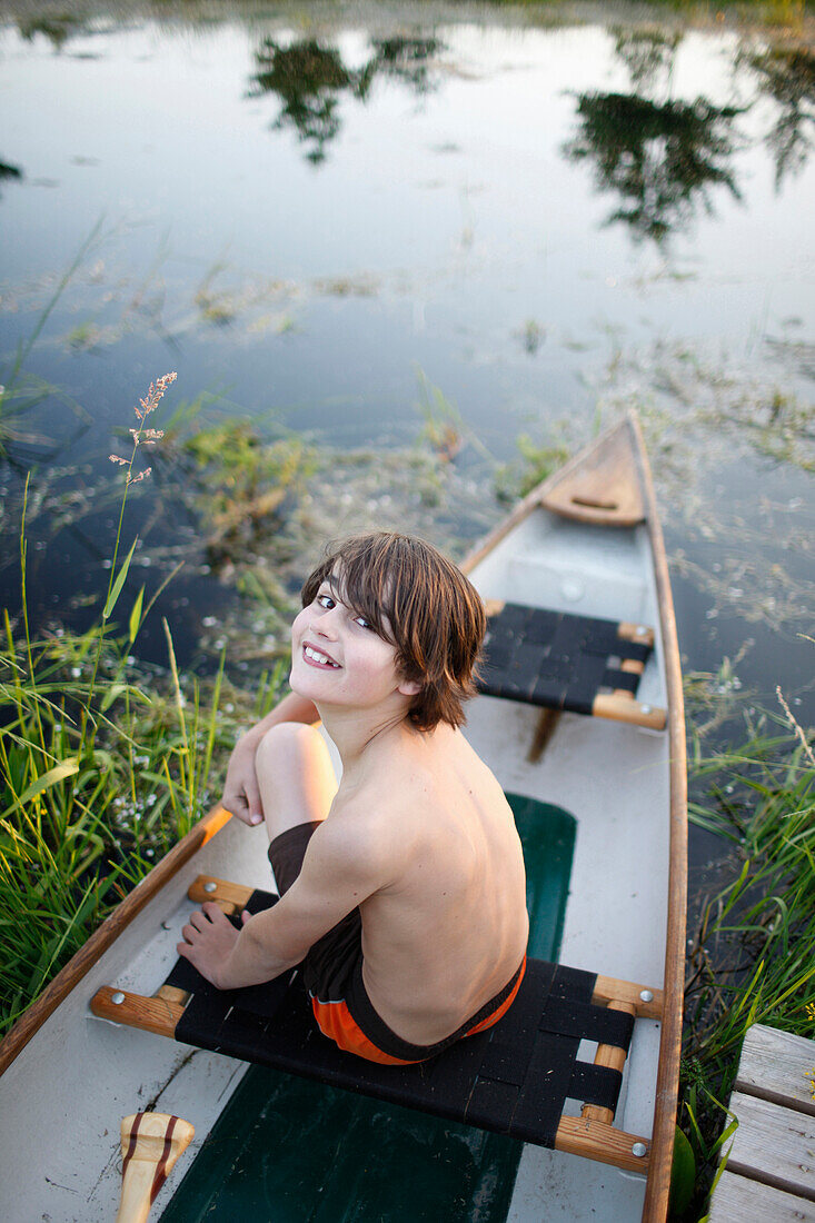 Junge sitzt in einem Kanu, Haus Strauss, Bauernkate in Klein Thurow, Roggendorf, Mecklenburg-Vorpommern, Deutschland