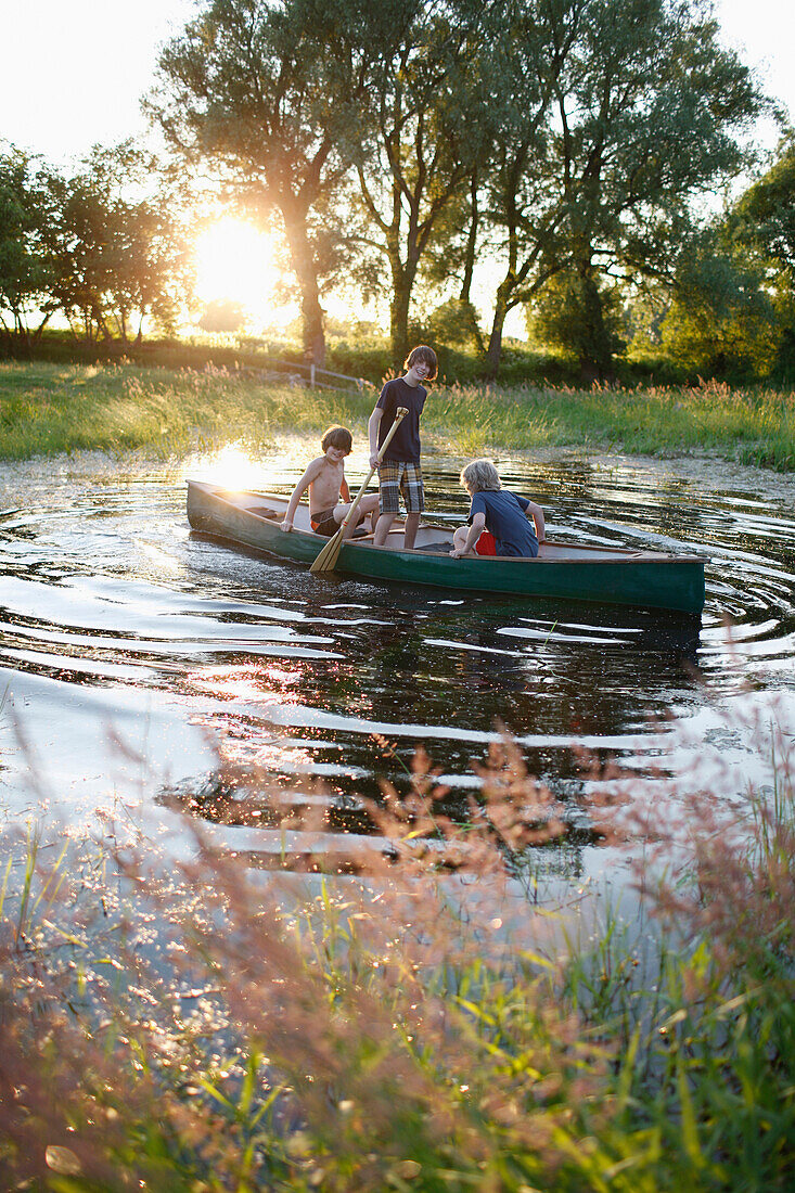 Three boys in a canoe on a pond, Klein Thurow, Roggendorf, Mecklenburg-Western Pomerania, Germany