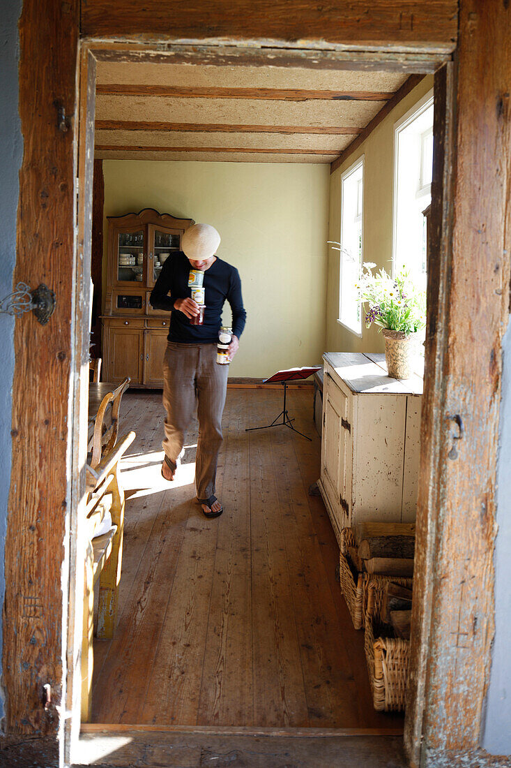 Mann balanciert Marmeladengläser durch ein Wohnzimmer, Haus Strauss, Bauernkate in Klein Thurow, Roggendorf, Mecklenburg-Vorpommern, Deutschland