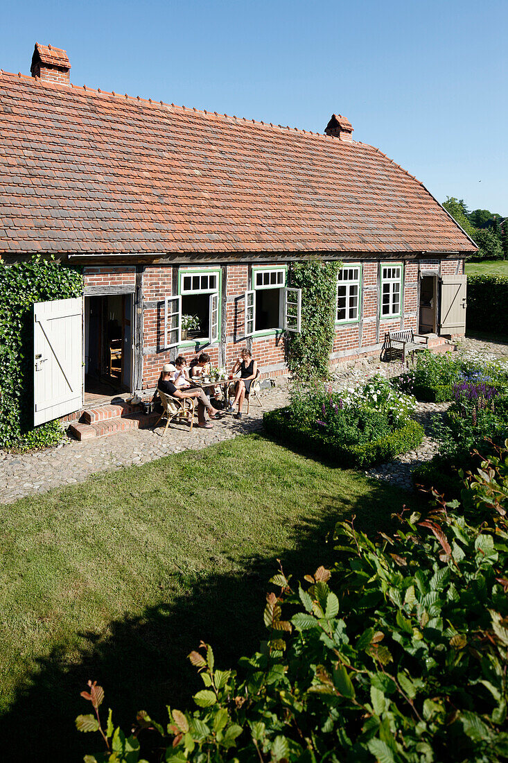 Familie beim Essen im Garten, Haus Strauss, Bauernkate in Klein Thurow, Roggendorf, Mecklenburg-Vorpommern, Deutschland