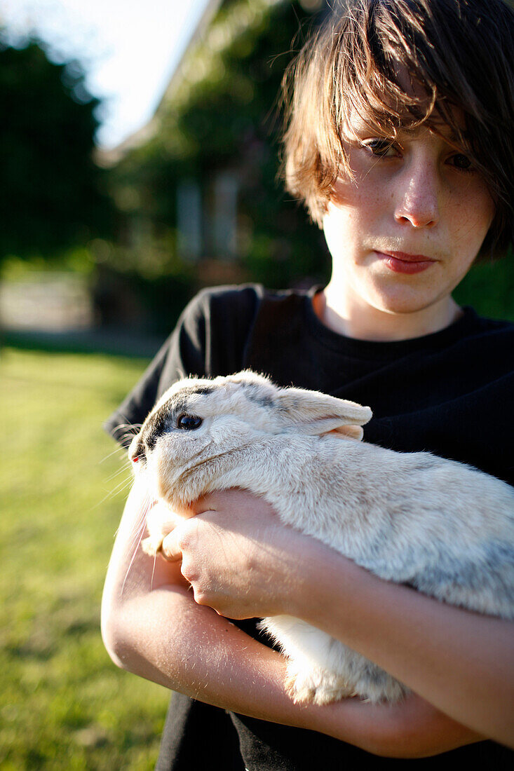 Junge mit Kaninchen im Arm, Haus Strauss, Bauernkate in Klein Thurow, Roggendorf, Mecklenburg-Vorpommern, Deutschland