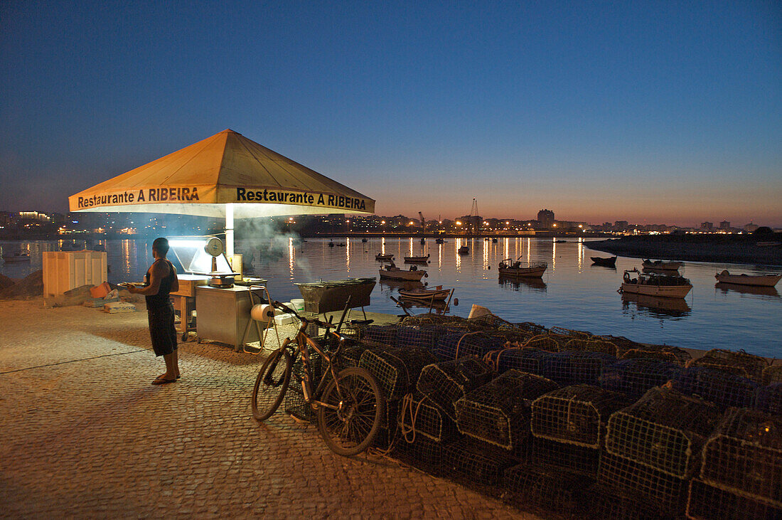 Fisch Grill am Rio Arade nach Sonnenuntergang, Blick über den Fluss mit Booten nach Portimao, Ferragudo, Zentralalgarve, Algarve, Portugal, Europa