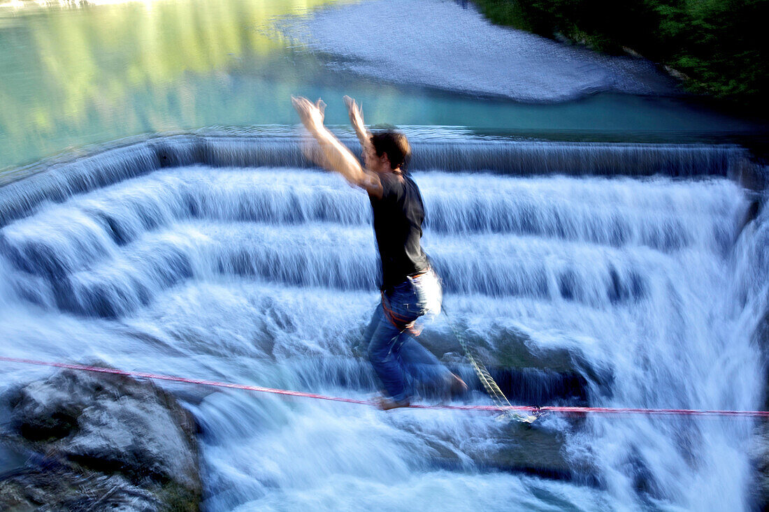 Young man balancing on a highline over a stream, Fuessen, Bavaria, Germany, Europe