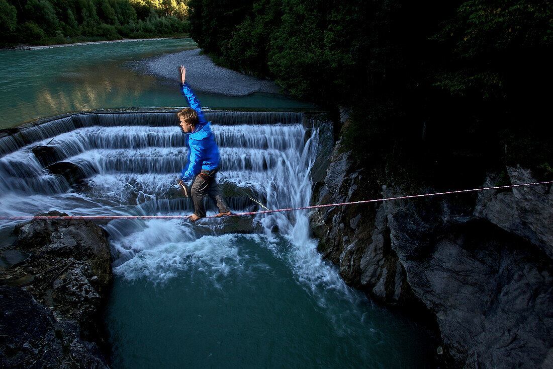 Young man balancing on a highline over a stream, Fuessen, Bayern, Deutschland, Europe