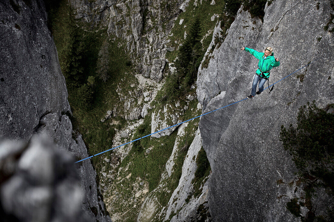 Junger Mann balanciert über eine Highline zwischen zwei Felsen, Oberammergau, Bayern, Deutschland, Europa